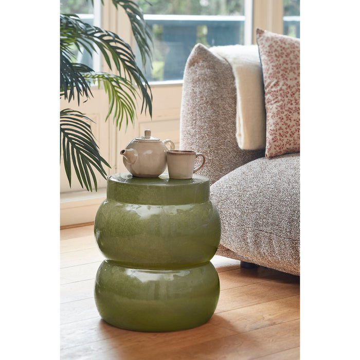 Green side table with a teapot and cup in a living room setting