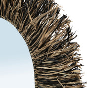 Close-up of a decorative mirror with wicker frame on a light blue background