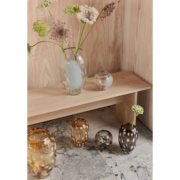 Vases with flowers on a wooden shelf against a wooden wall.
