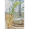 Glass vase with greenery on a table with a blurred outdoor background