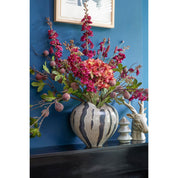Decorative floral arrangement in a zebra-striped vase against a blue wall.