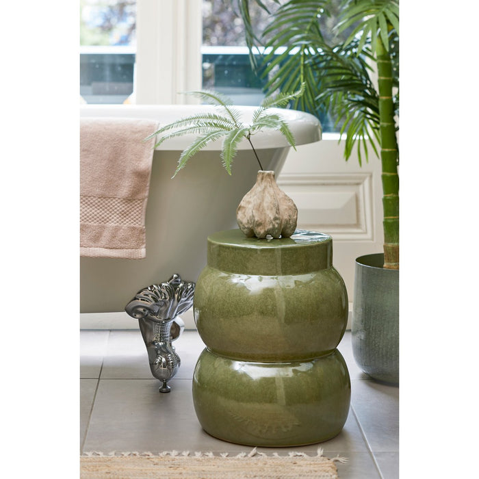 Green ceramic stool with decorative vase in a bathroom setting