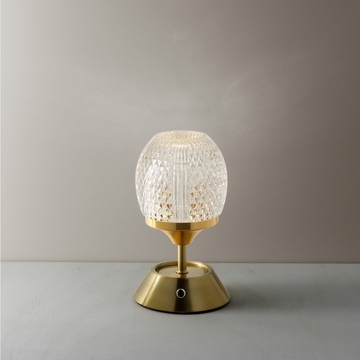 Table lamp with textured glass shade and gold base on a neutral background