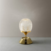 Table lamp with textured glass shade and gold base on a neutral background