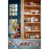 Wooden bookshelf with decorative items in a room with a blue door and colorful cushions.
