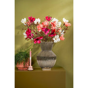 Decorative vase with flowers on a table against a green wall